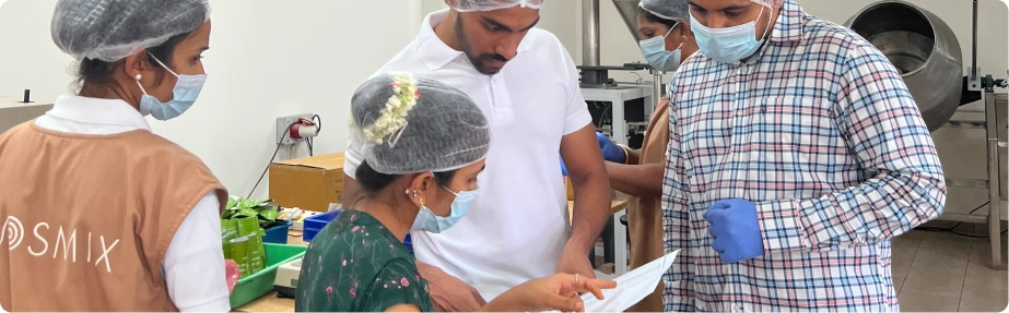 Team of workers  discussing a document inside a clean manufacturing facility.