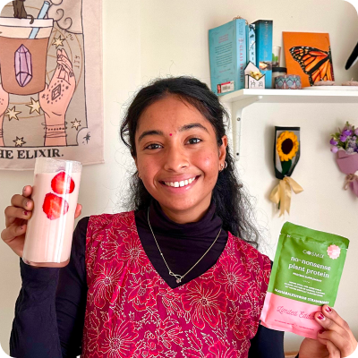Woman holding a strawberry protein shake and plant protein powder packet